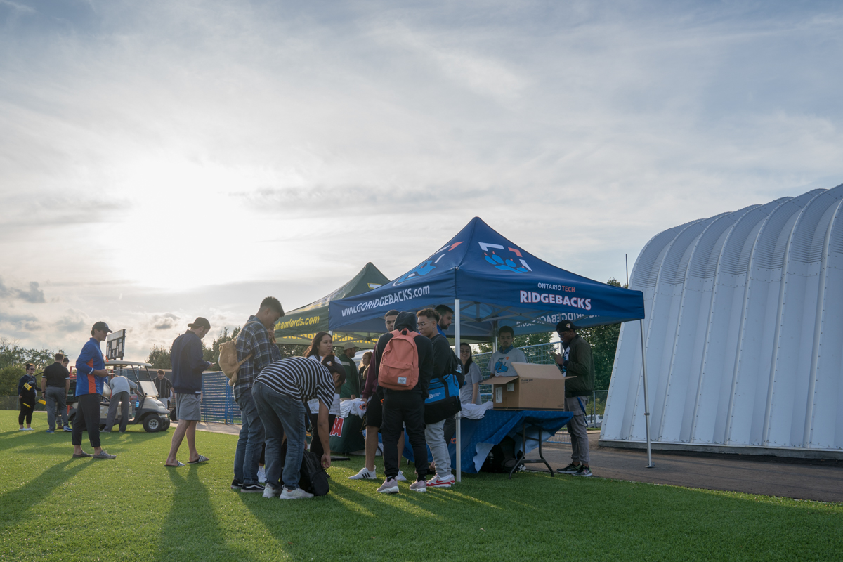 Students at an event booth on a large green field.