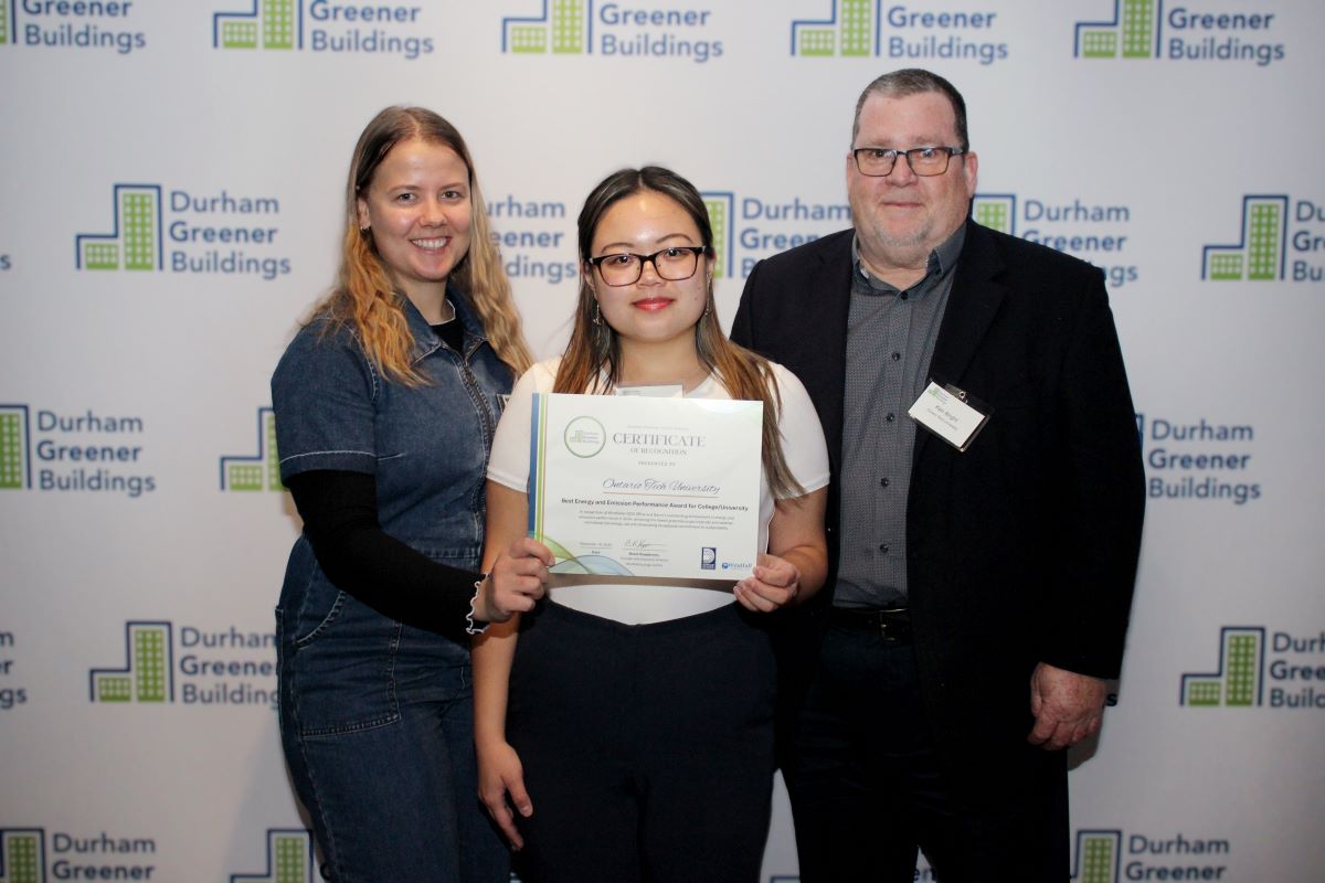 Three people stand with an award